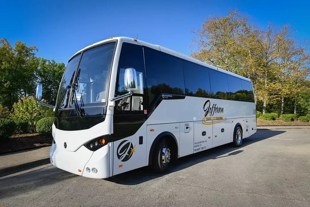 Modern white and black charter bus with Jefferson Tours branding parked in lot with trees and clear blue sky