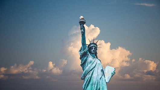 Statue of Liberty standing against blue sky with white clouds